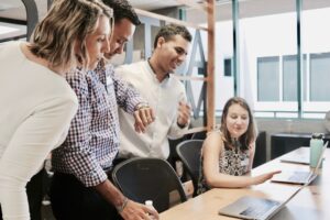 Team bespricht gemeinsam Abläufe an einem Tisch mit Laptops